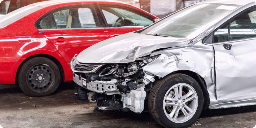 Ein silbernes Leasingauto steht mit einem Totalschaden in einer Werkstatt.
