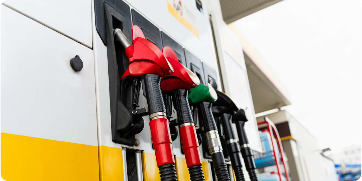 Fotografier von Zapfpistolen in Rot, Grün und Schwarz an einer Zapfsäule einer Tankstelle