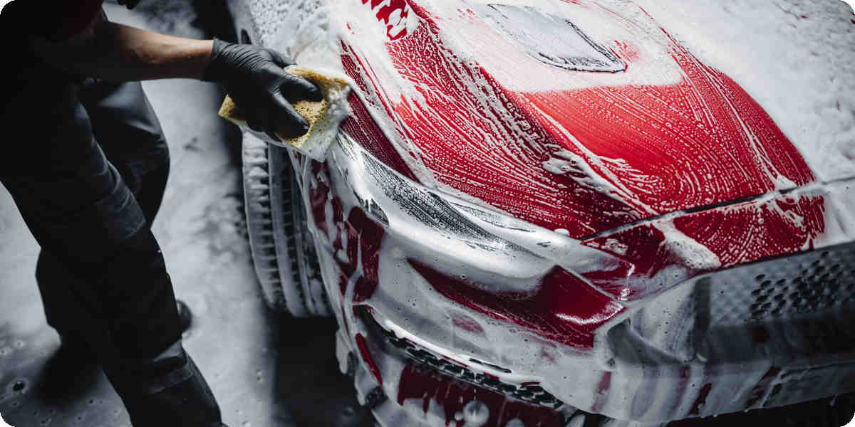 Ein Auto wird mit einem Schwamm gr&uuml;ndlich gereinigt.