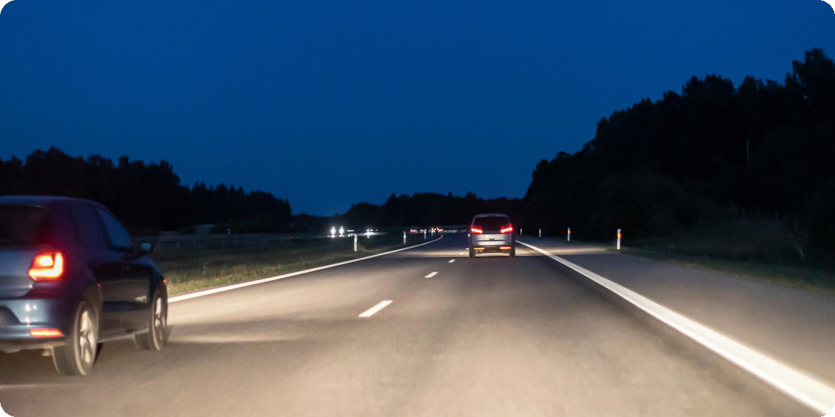 Autos fahren in der Nacht auf einer Umgehungsstraße mit Gegenverkehr.
