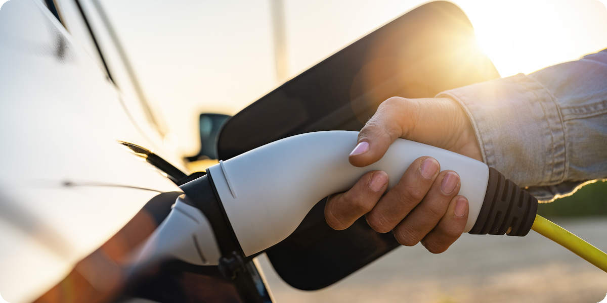 Alt-Text: Ein Elektroauto wird gerade per Ladestecker mit einer Ladesäule verbunden.